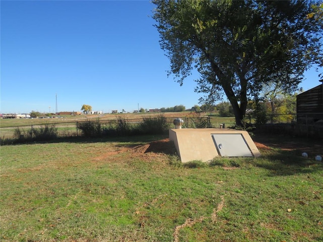 entry to storm shelter with a lawn and a rural view