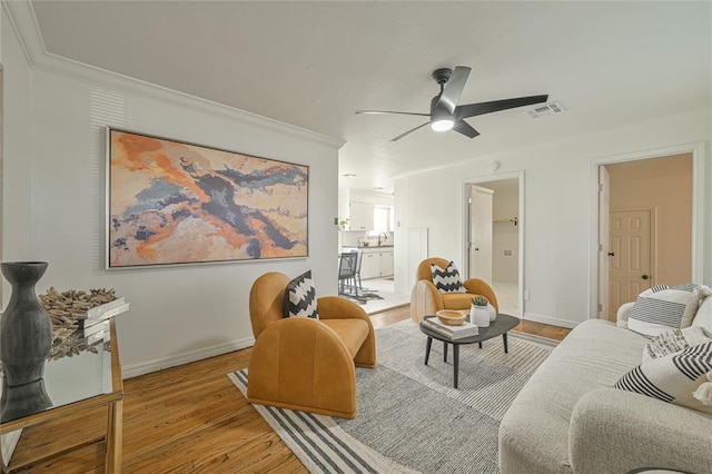 living room featuring light hardwood / wood-style flooring, ceiling fan, and ornamental molding