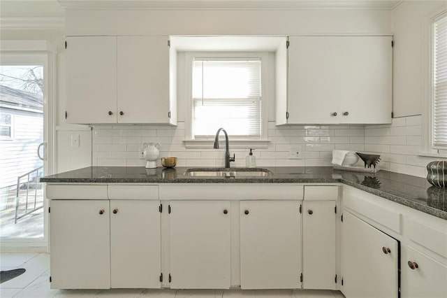 kitchen with backsplash, dark stone countertops, sink, and white cabinets