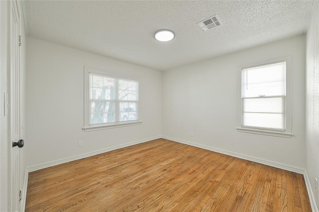 unfurnished room featuring light hardwood / wood-style flooring and a textured ceiling