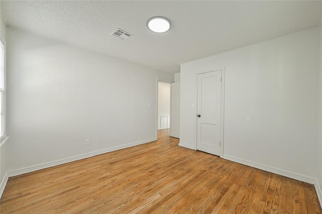 spare room featuring light hardwood / wood-style flooring and a textured ceiling