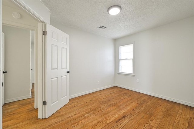 spare room featuring a textured ceiling and light wood-type flooring