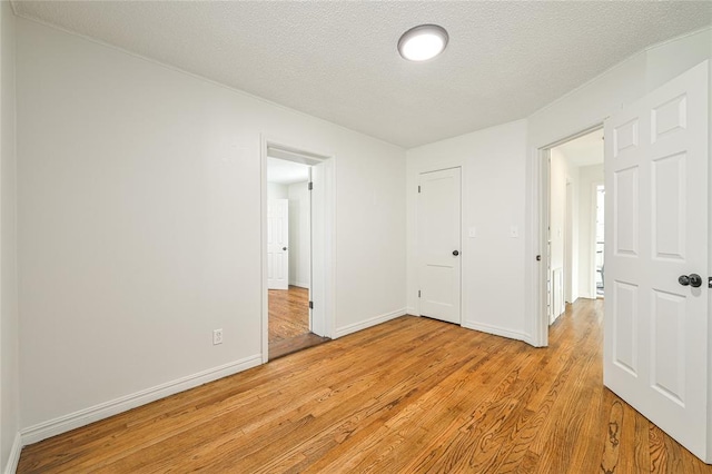 unfurnished bedroom featuring a closet, a textured ceiling, and light hardwood / wood-style flooring