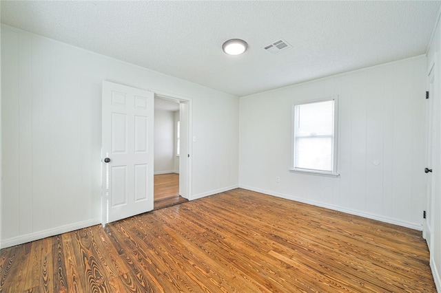 unfurnished room featuring wood-type flooring and a textured ceiling