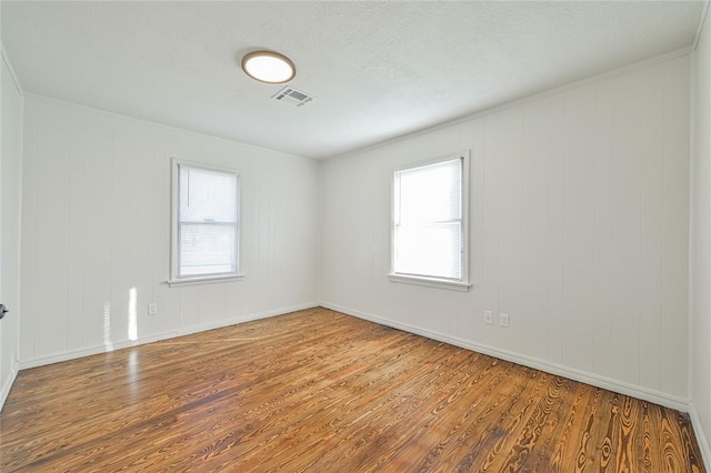 empty room with hardwood / wood-style floors and a healthy amount of sunlight