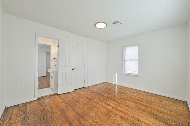 unfurnished bedroom featuring hardwood / wood-style floors and connected bathroom