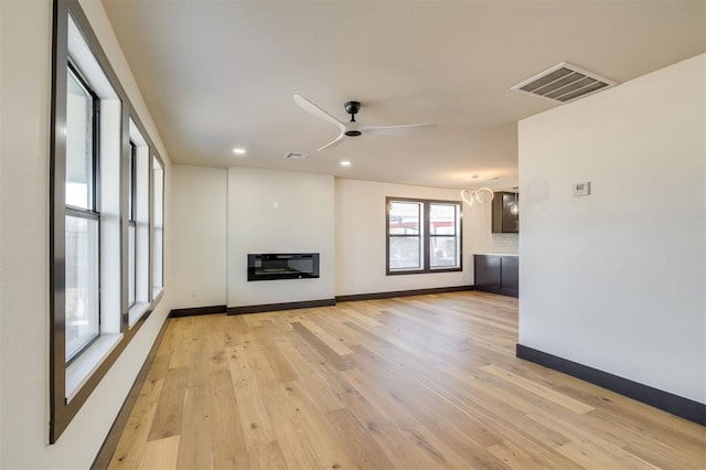 unfurnished living room featuring light wood-type flooring, heating unit, and ceiling fan