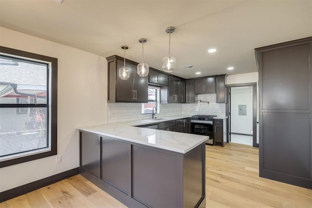 kitchen with kitchen peninsula, decorative backsplash, light hardwood / wood-style floors, and sink