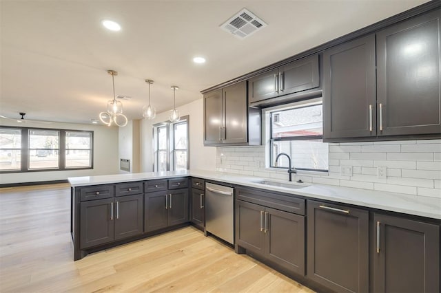 kitchen featuring sink, stainless steel dishwasher, decorative light fixtures, light hardwood / wood-style floors, and kitchen peninsula