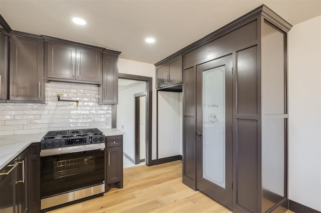 kitchen featuring dark brown cabinets, light hardwood / wood-style flooring, stainless steel range with gas cooktop, and light stone counters