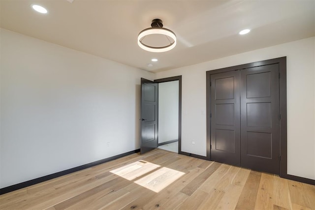 unfurnished bedroom with light wood-type flooring and a closet