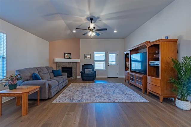 living room with ceiling fan, a fireplace, hardwood / wood-style floors, and vaulted ceiling