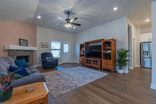 living room featuring dark hardwood / wood-style flooring, a brick fireplace, and ceiling fan