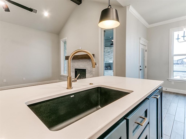 kitchen with sink, hanging light fixtures, vaulted ceiling, ceiling fan, and ornamental molding