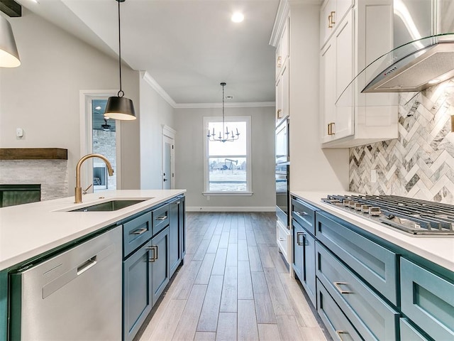 kitchen with backsplash, wall chimney exhaust hood, stainless steel appliances, sink, and white cabinets