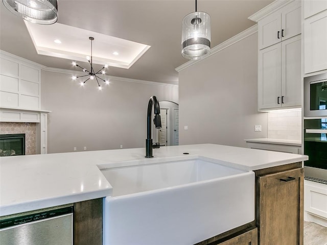 kitchen with white cabinetry, sink, a chandelier, a fireplace, and appliances with stainless steel finishes