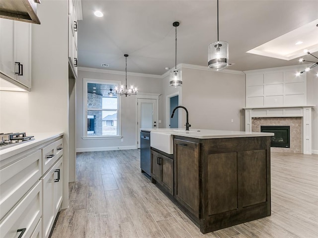 kitchen with a center island with sink, white cabinets, sink, light wood-type flooring, and stainless steel appliances