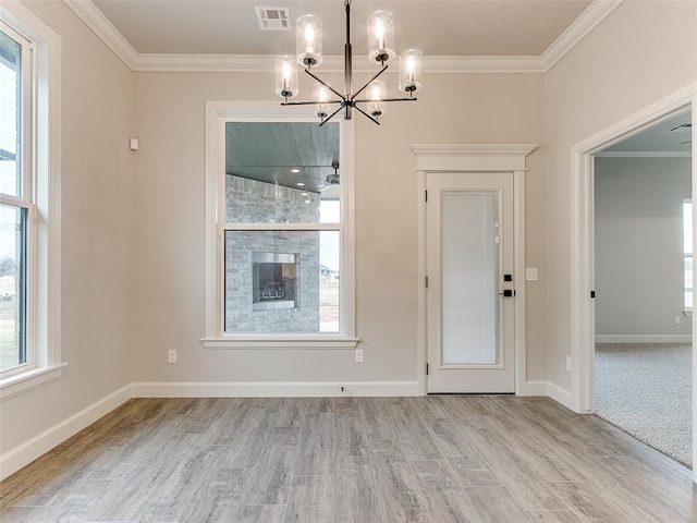 unfurnished dining area with a tiled fireplace, a chandelier, light hardwood / wood-style floors, and ornamental molding