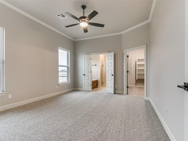 unfurnished bedroom with a spacious closet, a closet, ceiling fan, and ornamental molding