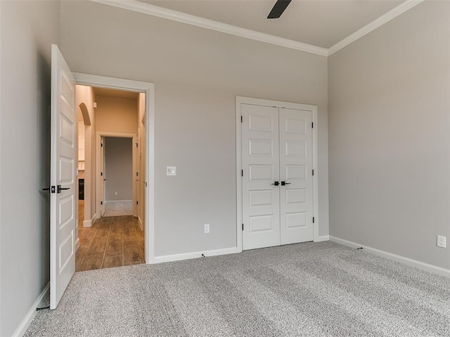 unfurnished bedroom with carpet flooring, ceiling fan, crown molding, and a closet