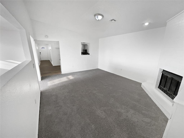 unfurnished living room with dark colored carpet and a fireplace