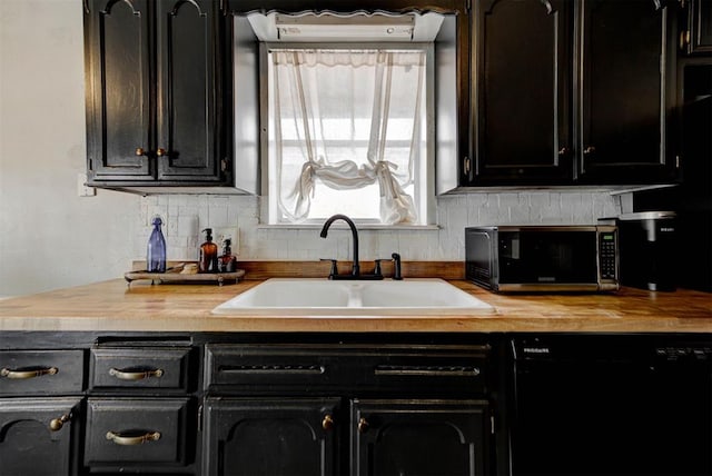 kitchen with a sink, dark cabinetry, dishwasher, tasteful backsplash, and stainless steel microwave