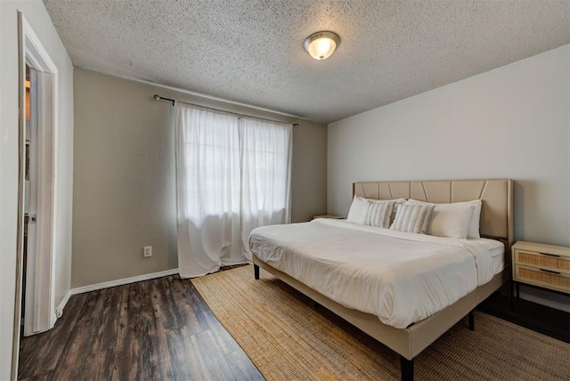 bedroom with baseboards, dark wood finished floors, and a textured ceiling