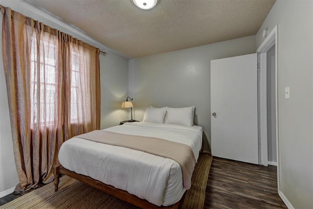 bedroom with dark wood-style flooring, a textured ceiling, and baseboards