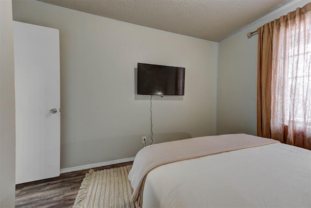 bedroom featuring dark wood-type flooring, a textured ceiling, and baseboards