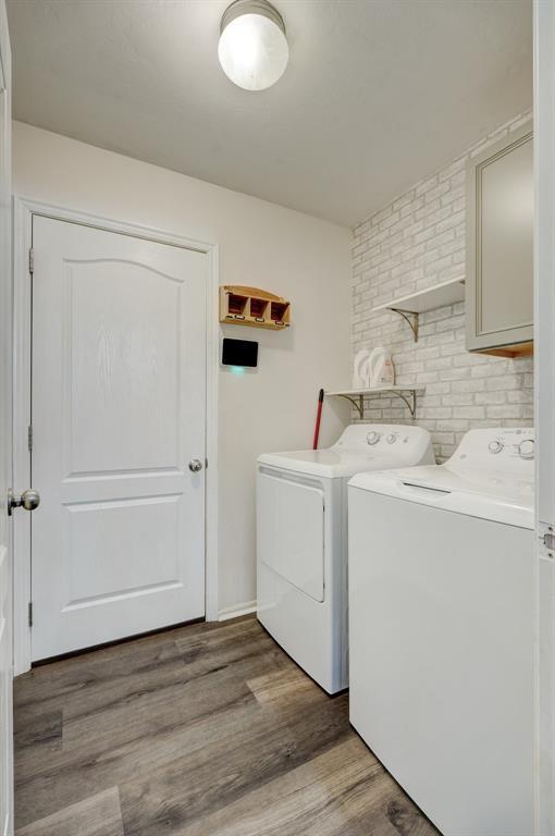 clothes washing area featuring cabinets, dark hardwood / wood-style flooring, and washing machine and clothes dryer