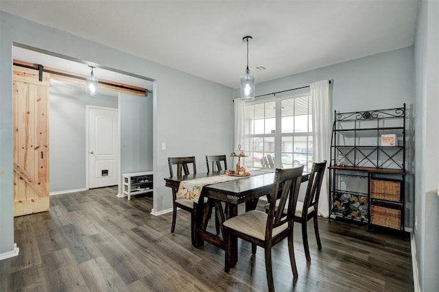 dining room featuring a barn door and dark wood-type flooring