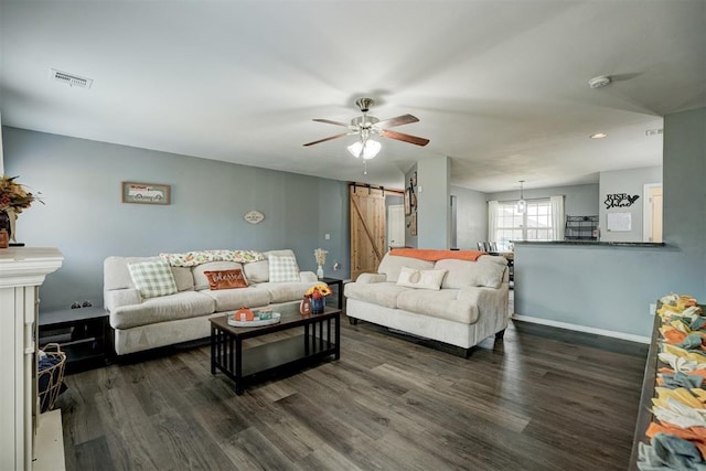 living room with a barn door, ceiling fan, and dark hardwood / wood-style flooring