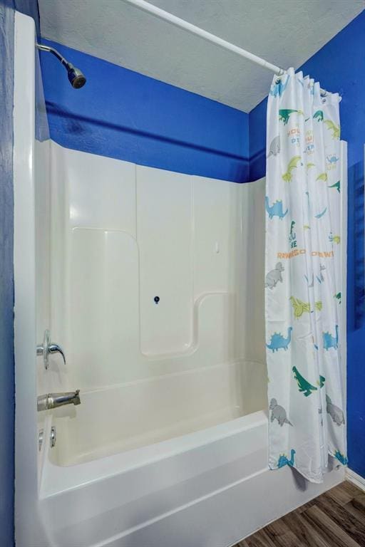 bathroom with shower / bath combination with curtain, wood-type flooring, and a textured ceiling