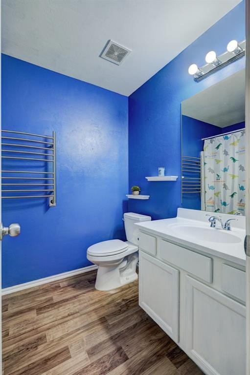 bathroom featuring wood-type flooring, vanity, toilet, and walk in shower