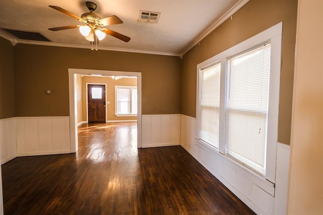 spare room featuring ceiling fan, plenty of natural light, ornamental molding, and dark wood-type flooring