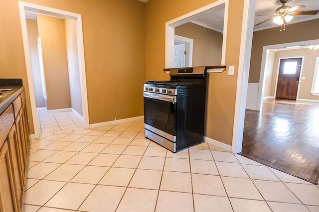 kitchen with light tile patterned floors, ceiling fan, crown molding, and stainless steel range with gas stovetop