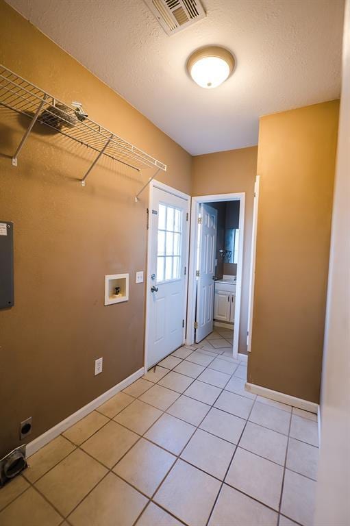 laundry room with hookup for an electric dryer, light tile patterned floors, a textured ceiling, and washer hookup