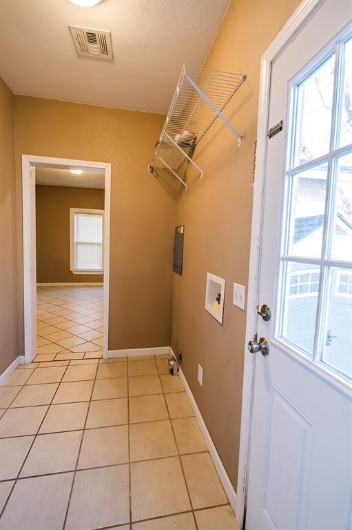 clothes washing area with hookup for a washing machine and light tile patterned floors