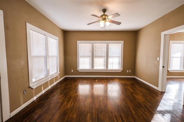 spare room featuring dark hardwood / wood-style floors, ceiling fan, and a healthy amount of sunlight