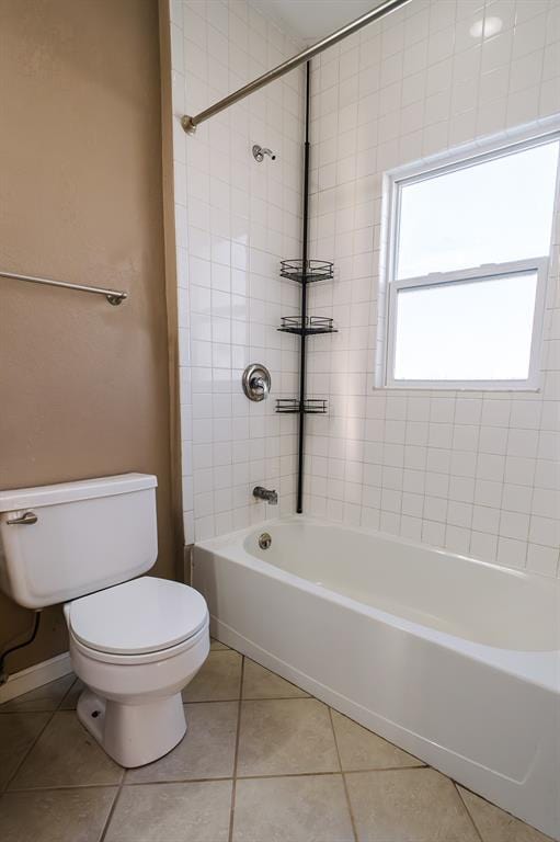 bathroom featuring tile patterned floors, toilet, and tiled shower / bath