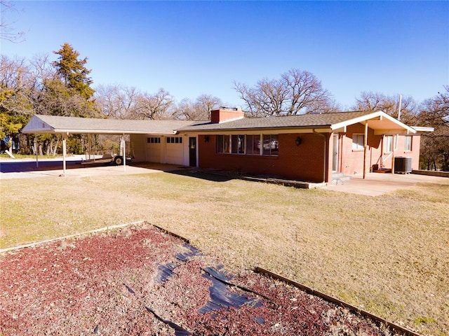 back of house with a yard, central AC unit, and a carport