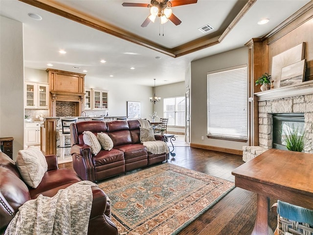 living room featuring crown molding, dark hardwood / wood-style floors, a raised ceiling, and a fireplace