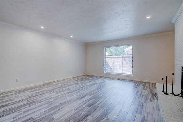 unfurnished room with light wood-type flooring, ornamental molding, and a brick fireplace