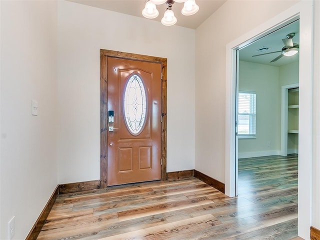 entrance foyer with ceiling fan with notable chandelier and light hardwood / wood-style flooring