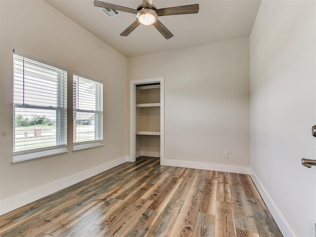 unfurnished bedroom with a walk in closet, dark hardwood / wood-style flooring, a closet, and ceiling fan