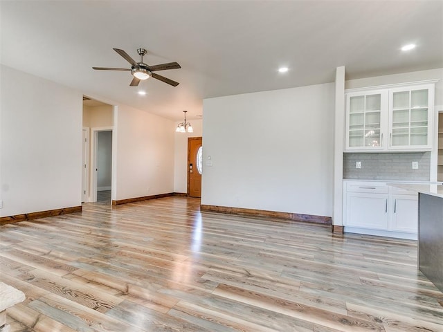 unfurnished living room featuring light hardwood / wood-style floors and ceiling fan with notable chandelier