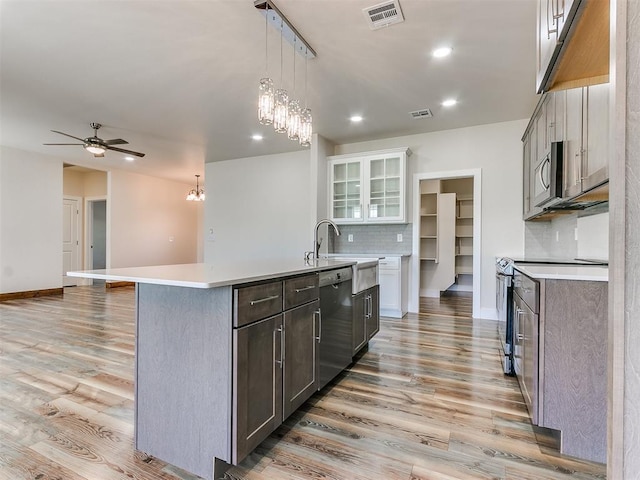 kitchen with backsplash, light hardwood / wood-style floors, a kitchen island with sink, white cabinets, and appliances with stainless steel finishes