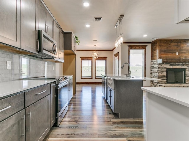 kitchen with tasteful backsplash, pendant lighting, stainless steel appliances, and a notable chandelier