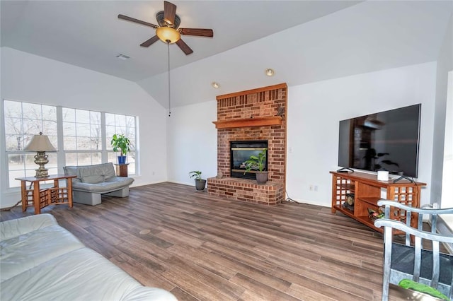 living room featuring ceiling fan, hardwood / wood-style floors, vaulted ceiling, and a brick fireplace