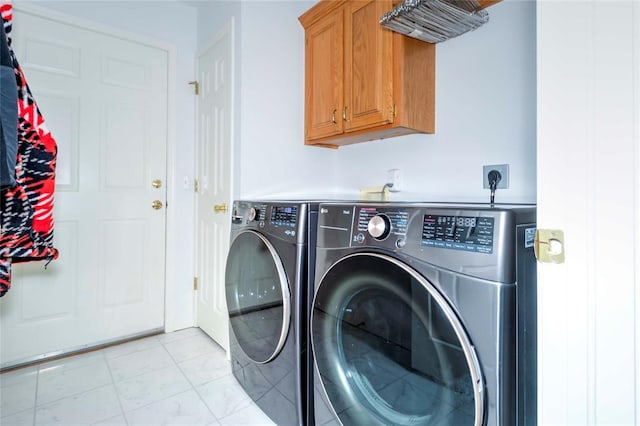 laundry room with cabinets, light tile patterned floors, and washing machine and clothes dryer